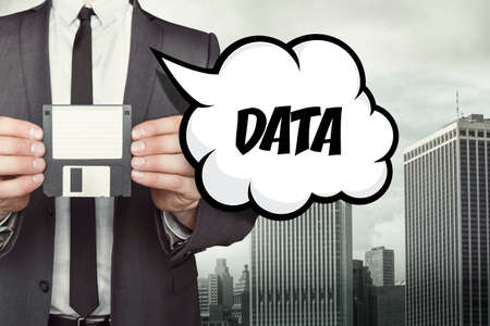 Data text on speech bubble with businessman holding diskette on cityscape backgroundの写真素材
