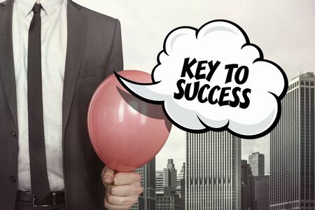 Key to success text on speech bubble with businessman holding balloon on cityscape backgroundの写真素材
