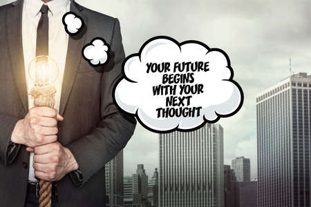 Your future begins with your next thought text on speech bubble with businessman holding lamp on city backgroundの写真素材