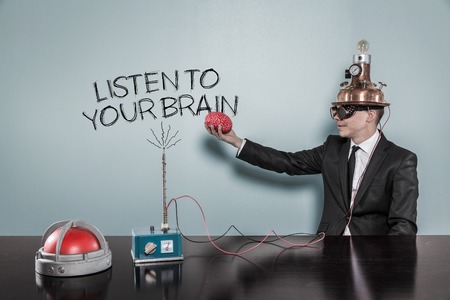 Listen to your brain concept with businessman holding brain at hand in officeの写真素材