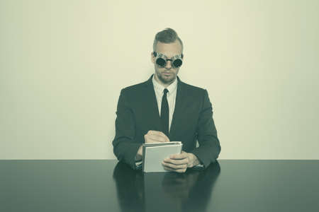 Businessman sitting at office desk with vintage gogglesの写真素材