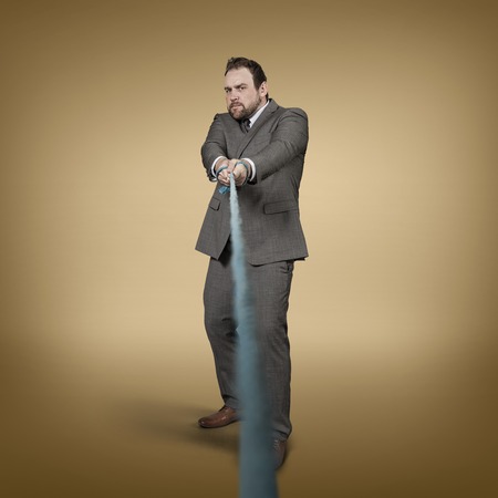 Businessman pulling rope at office - studio shotの写真素材