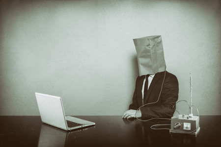 Vintage businessman sitting at office desk with laptopの写真素材
