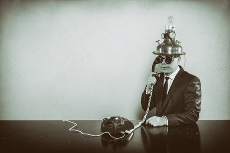 Vintage businessman sitting at office desk with phoneの写真素材