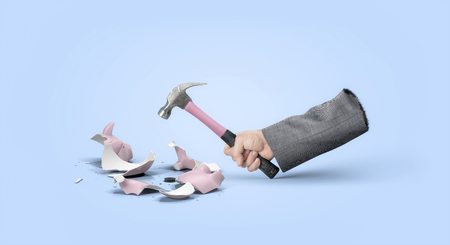 Hand with hammer breaking piggy bankの写真素材