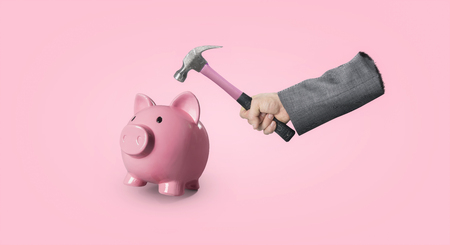 Hand with hammer breaking piggy bankの写真素材
