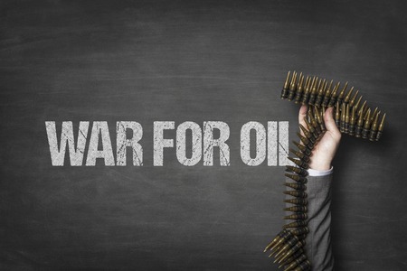 War for oil text on blackboard with businessman hand holding ammunition