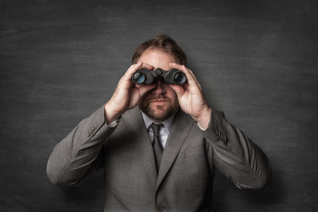 Businessman in a suit watching with binoculars