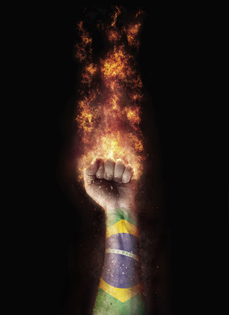Brazil flag in a hand which is on a fireの写真素材