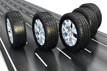 Creative automotive industrial concept: set of black car auto rubber wheels driving the asphalt highway road isolated on white backgroundの写真素材