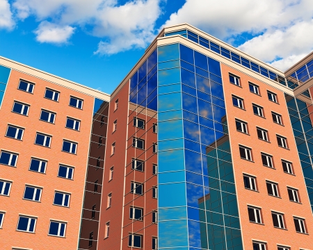 Modern glass reflective city business office buildings over blue sky with cloudsの写真素材