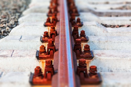 Creative abstract railway transportation industry and railroad cargo shipping business infrastructure industrial concept: macro view of metal train rail and sleepers with selective focus effectの写真素材
