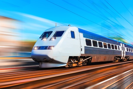Railroad travel and railway tourism transportation industrial concept: scenic summer view of modern high speed passenger commuter train on tracks at the station platform with motion blur effect Railroad travel and railway tourism transportation industrial concept: scenic summer view of modern high speed passenger commuter train on tracks at the station platform with motion blur effect