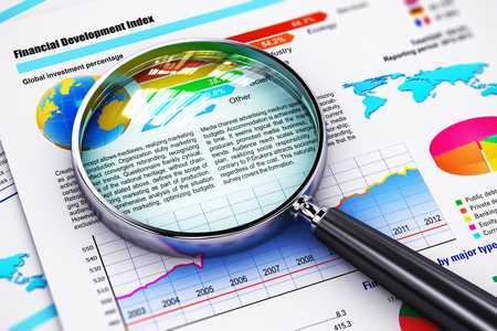 Creative abstract business success solution, document paperwork, office financial growth and development technology concept: macro view of magnifying glass lens or magnifier loupe on financial reports with color graphs and charts with selective focus effeの写真素材