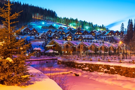Scenic winter view of mountain ski resort with snowy house cottages with forest and skiing slope in Bukovel, Ukraineの写真素材