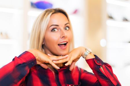 Head and shoulders portrait of young attractive smiling and dreaming woman with long blonde hair in the fashion wear garments apparel storeの写真素材