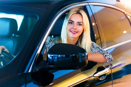 Happy smiling young woman in the modern luxury car