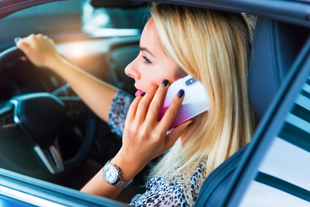 Young woman driver talking by phone in the modern luxury carの写真素材