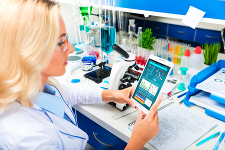 Young attractive woman scientist using tablet computer in the scientific chemical laboratoryの写真素材