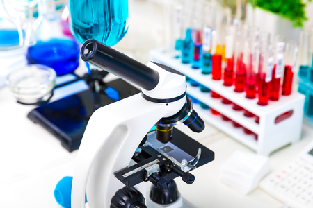 Creative abstract chemistry development, medicine, pharmacy, biology, biochemistry and research technology concept: table with scientific chemical laboratory equipment - microscope, test tubes with color liquid substance samples, vials, flasks, report documents etc. with selective focus effectの写真素材