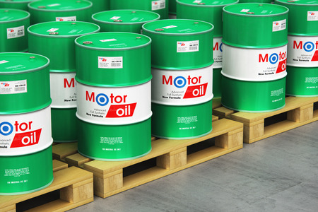 Creative abstract automotive industry and auto repair service and maintenance concept: 3D render illustration of the group of green stacked metal drum canisters or barrel containers with car motor engine liquid synthetic oil lubricant on wooden shipping pallets in the industrial storage warehouse with selective focus effectの写真素材