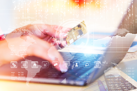 Creative abstract E-business, online shopping, internet payments and banking security concept: young woman working on her laptop or notebook and holding a gold credit card in her handの写真素材