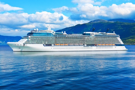 Big white cruise liner ship in the fjord of Norway, Scandinavia with deep blue sea or ocean, mountains and cloudsの写真素材