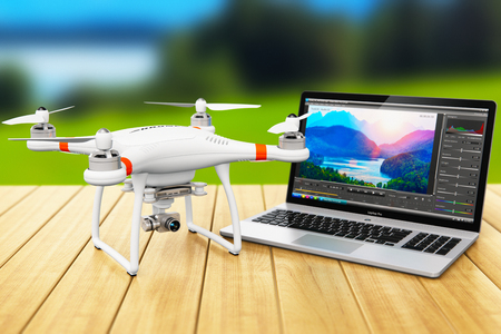 Creative abstract 3D render illustration of the black professional quadcopter drone and laptop of notebook computer PC with video and footage editing software on screen display on the wooden table outdoors with selective focus bokeh blur effectの写真素材
