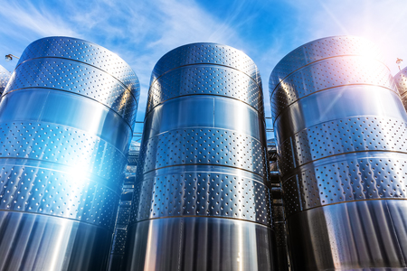 Row of the shiny stainless steel storage tank containers at the chemical plant factory against blue sky with cloudsの写真素材