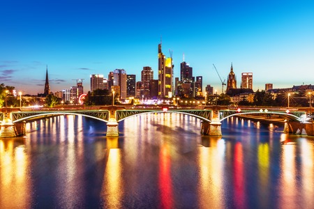 Scenic summer evening view of the business corporate downtown bank district with high tall skyscraper buildings and illuminated bridge over the Main River in Frankfurt am Main, Germanyの写真素材