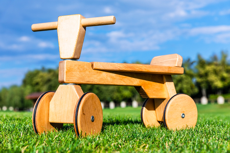 Wooden children runbike on the green grass field in the garden or park nature outdoorsの写真素材