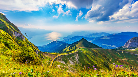 Scenic summer panorama from Rochers de Naye mountain peak with green grassy hills, flower meadows and Geneva Lake in Alps, Switzerlandの写真素材