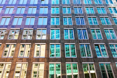 Creative abstract architectural style contrast background: old house and modern high skyscraper building reflect in glass mirror windows in the city streetの写真素材