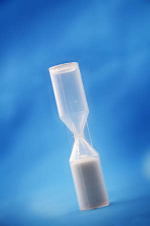 Plastic sand timer against a blue backdrop