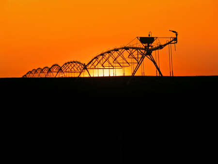 Water sprinklers silhouetted in prarie lands, sunset in background.の写真素材
