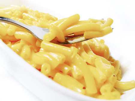Close-up of macaroni and cheese on a fork over noodles in white dish on white backgroundの写真素材