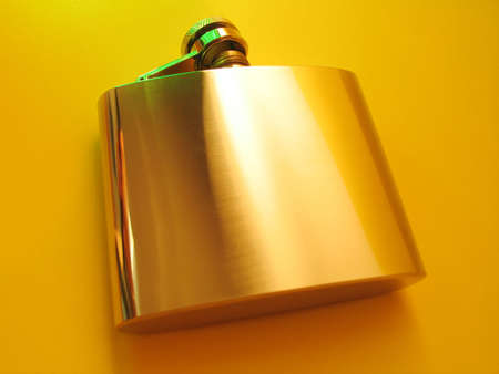 Stainless steel flask on a bright yellow background with a few highlights of green light.の写真素材
