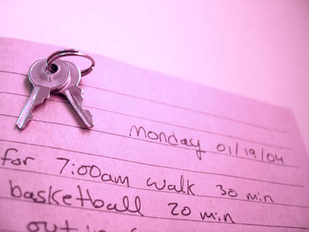 An open journal with a set of keys sitting on the top of the open book. Hand writing inside.の写真素材