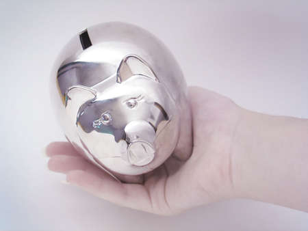 Hand holding a silver piggy bank.の写真素材