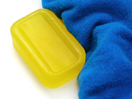 Yellow bar of semi-transparent soap next to a fluffy blue towel.の写真素材