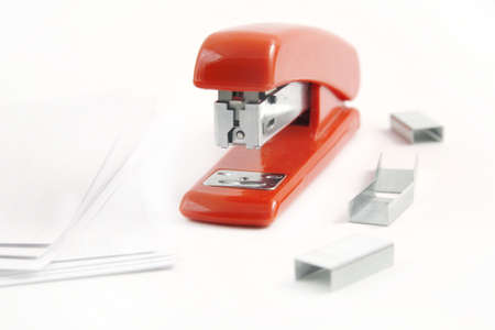 Red stapler with staples and assorted papersの写真素材
