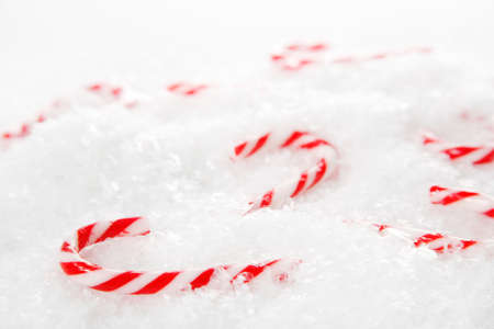 Miniature candy canes in a pile of snowflakesの写真素材