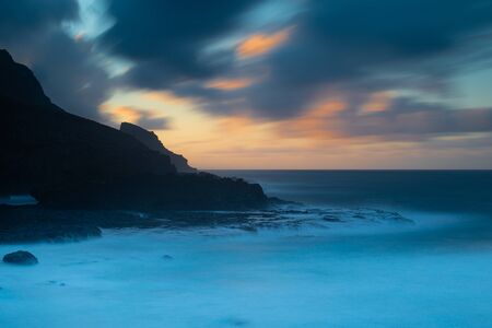 Sunset at sea in volcanic islandの写真素材