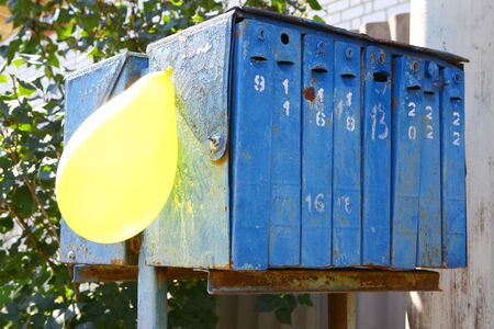 Row of old retro rusty blue mailboxes with yellow balloon
