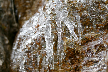 Icicles on a stone wall in the mountains of France in the winterの写真素材