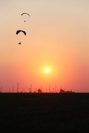 Two motodeltaplans in the sky against the background of sunsetの写真素材