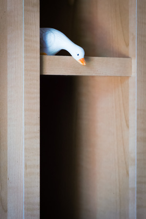 Old ornament shaped like a goose on wood cabinetの写真素材