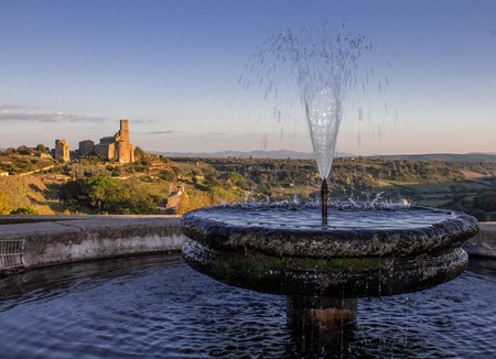 A beautiful fountain and an ancient cathedral in the background illuminated by the last rays of sunの写真素材