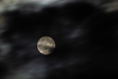 The moon circled by ghostly clouds moved by a strong windの写真素材