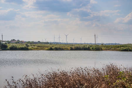 Windwheels, lake and a field in rural Ukraine. Wind farm near the villageの写真素材